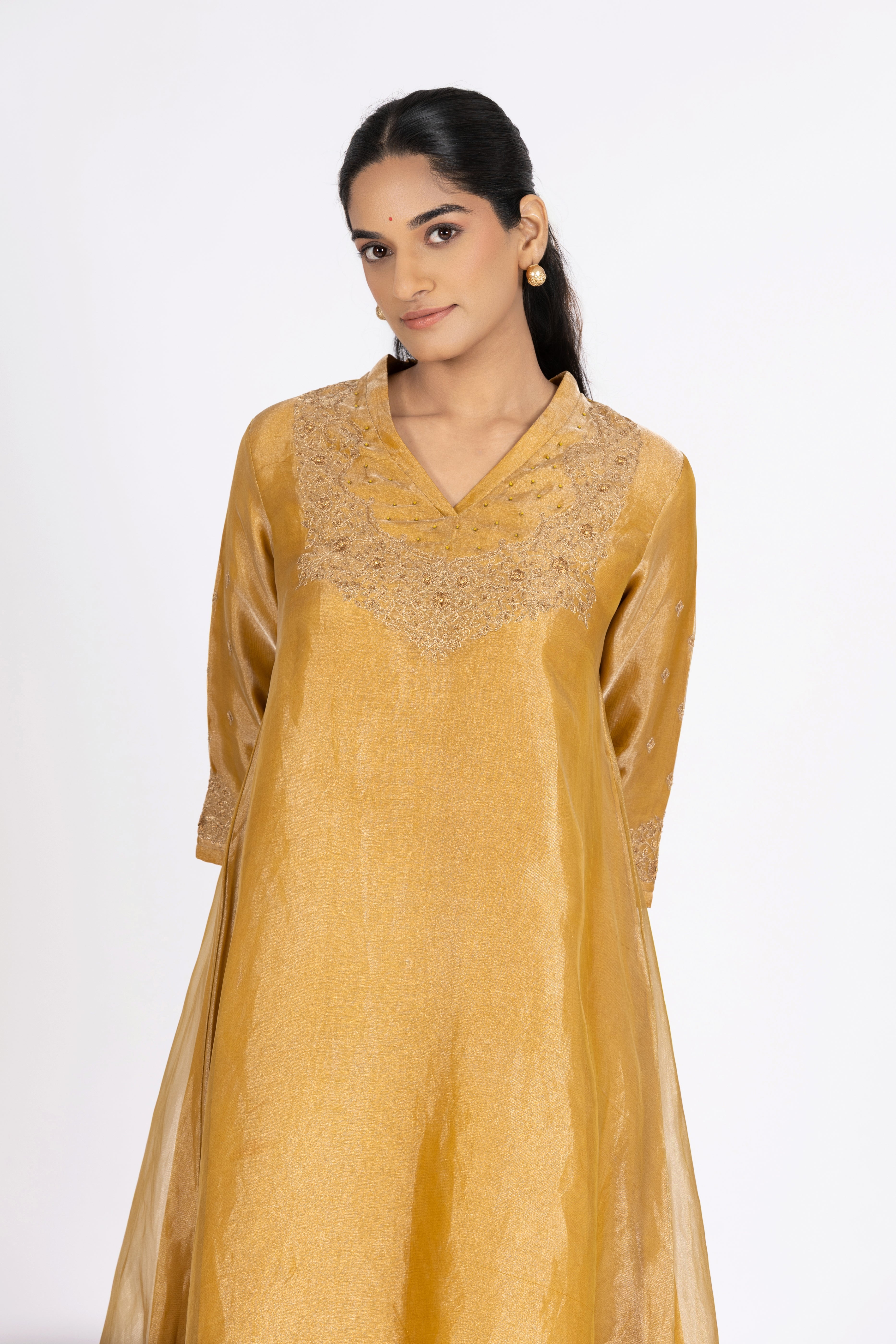 Woman wearing a Yellow Tissue kurta with gold embroidery on a white background