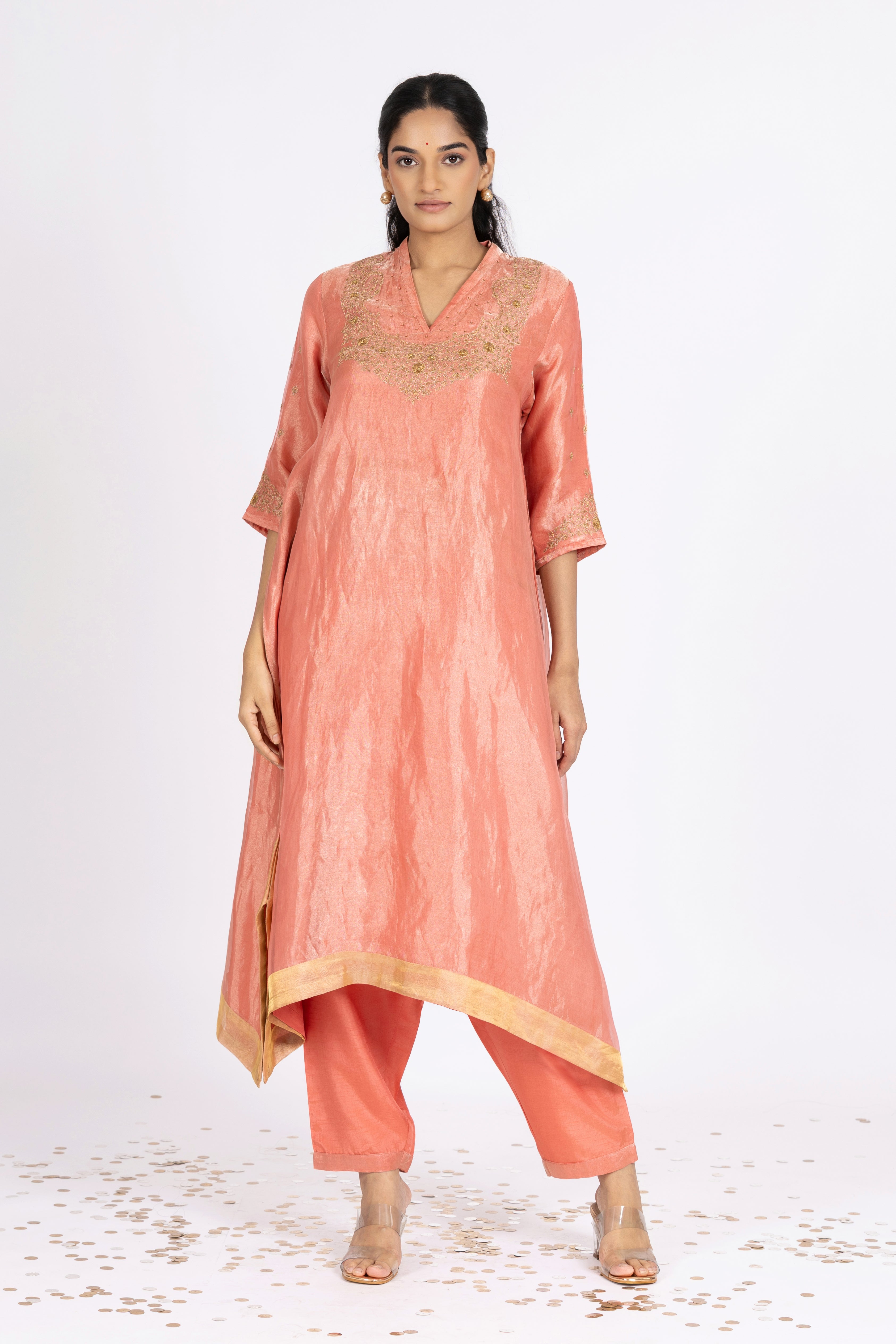 Woman wearing a peach-colored kurta with pants on a white background