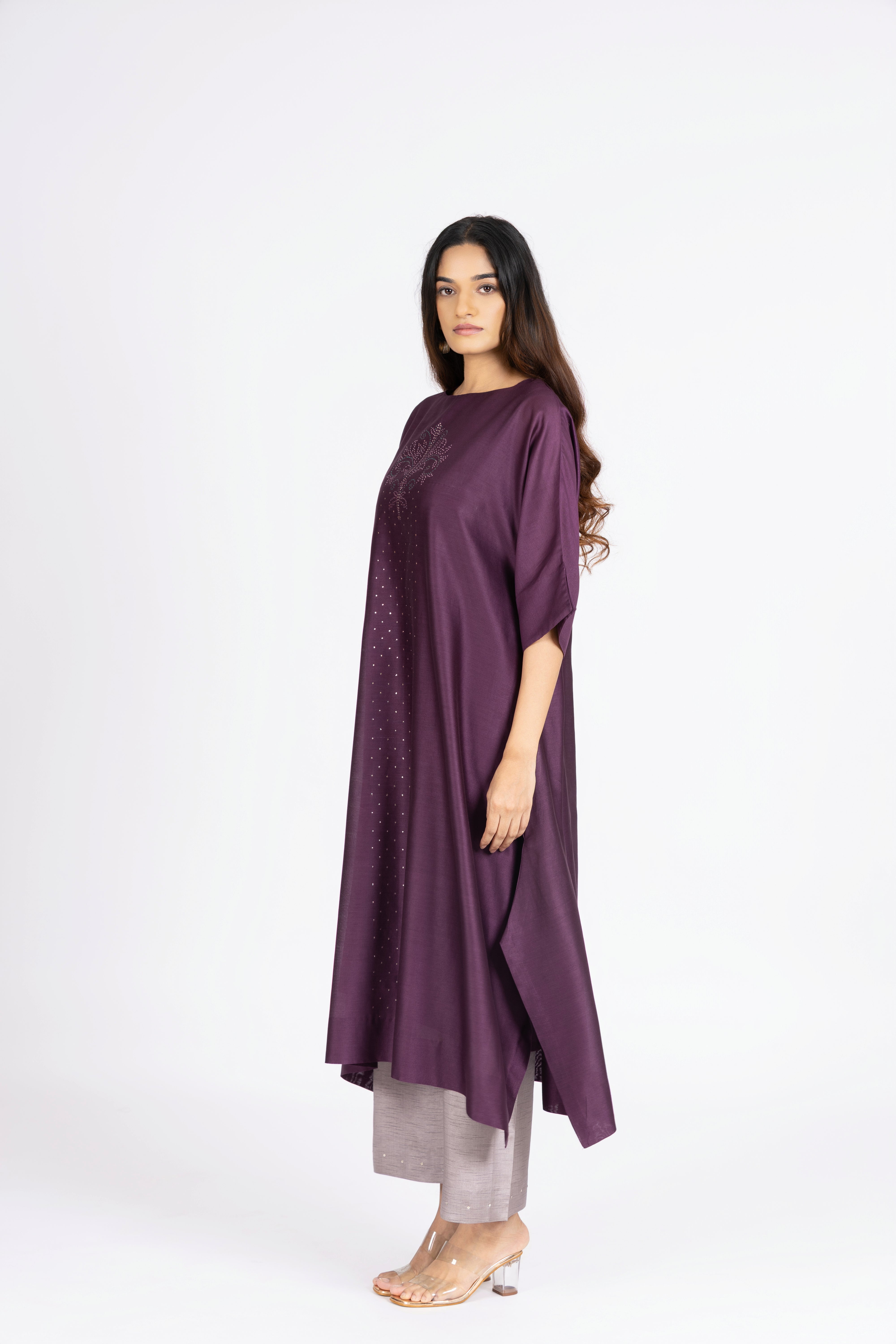 Woman wearing a long purple dress with a plain white background